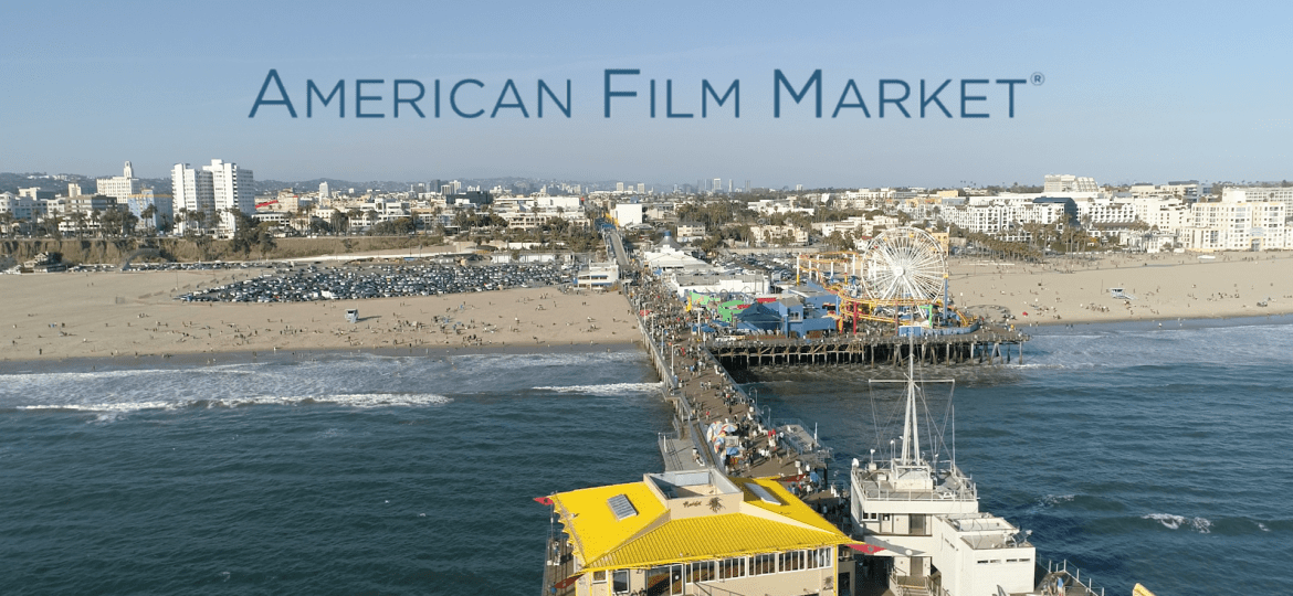 A view of Santa Monica pier, with ocean, then beach with the city in the background. The American Film Market written in blue across the sky.