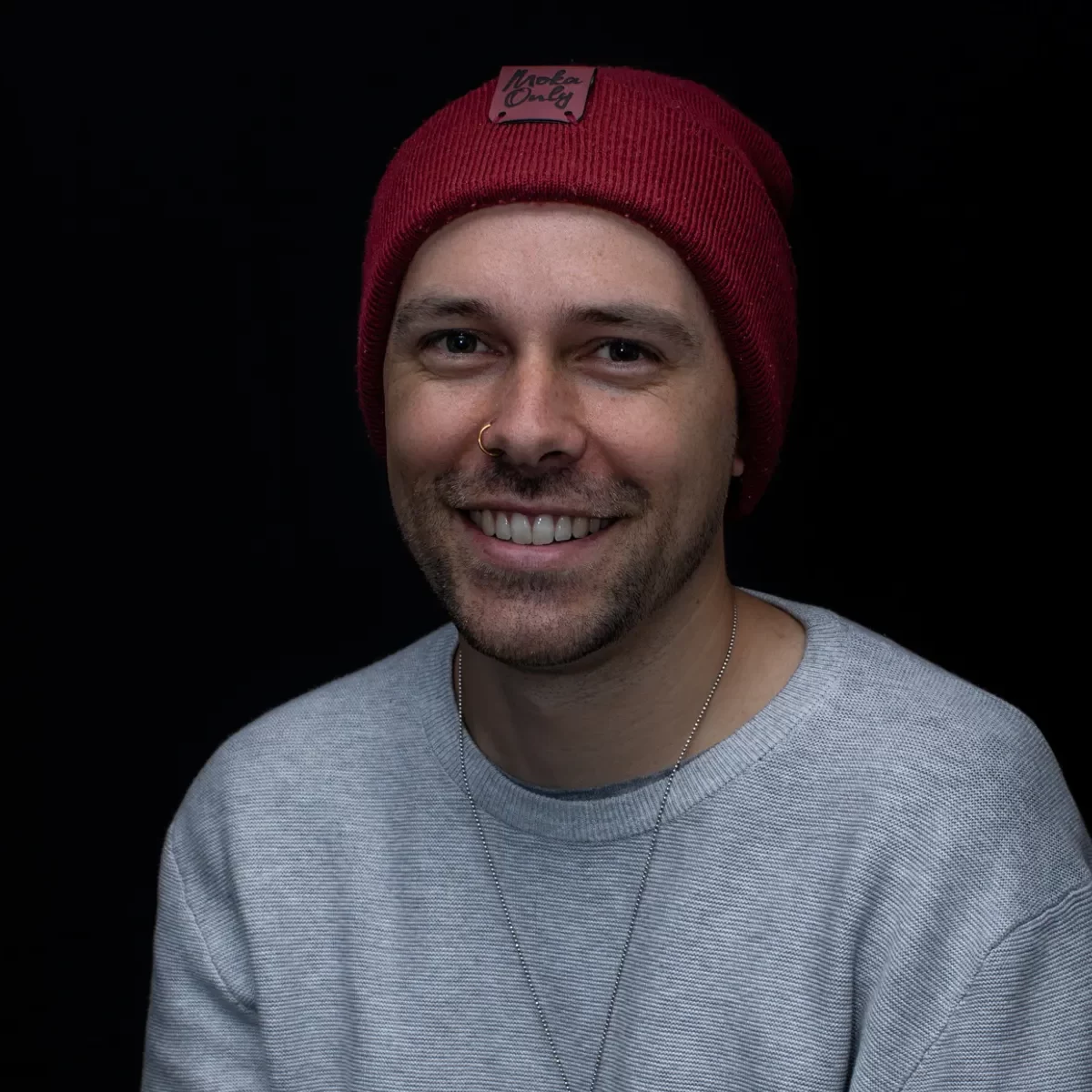 Beyond Content Staff member Fazz Farrell, head and shoulders image of a man smiling with a grey jumper and red beanie.